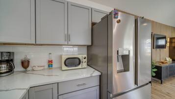 Una cocina moderna con un refrigerador de acero inoxidable, un microondas y una cafetera.