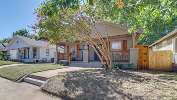A residential property with a front porch, a wooden fence, and a well-maintained lawn.