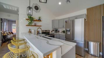 Una cocina moderna con una isla central, electrodomésticos de acero inoxidable y un comedor con sillas.