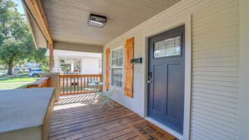 A covered porch with a wooden deck, a dark front door, and a mailbox.