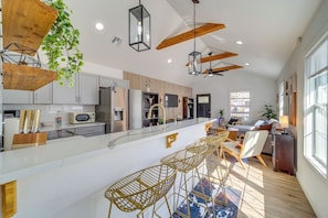 A modern kitchen with a central island, bar stools, and a dining area with a sofa and chairs. - Walk to Cherry Street Shops & Eats! Tulsa Escape (Tulsa)