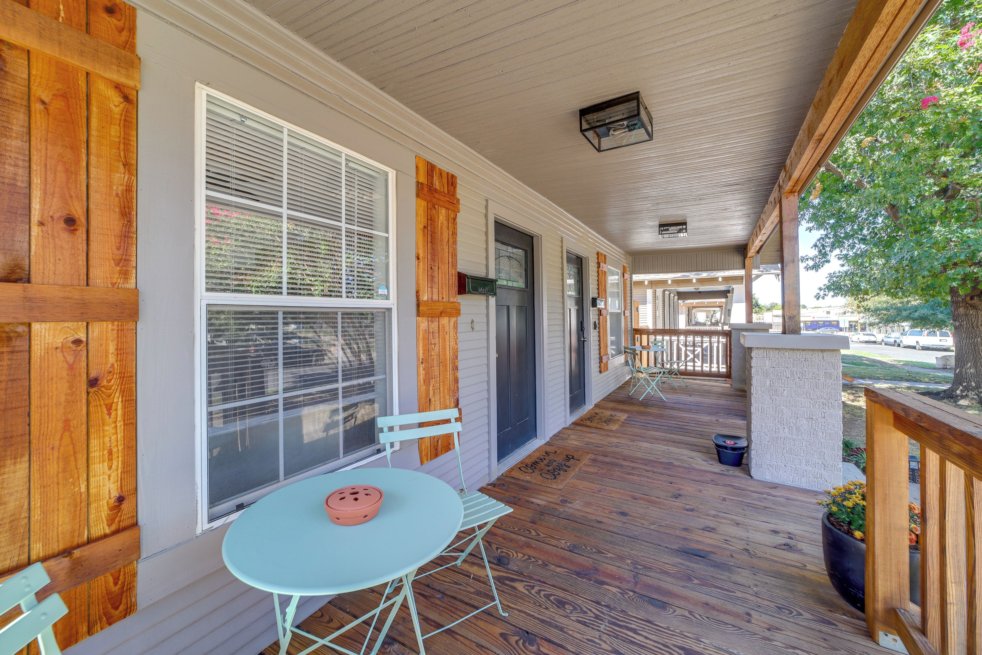 A covered porch with a table and chairs, wooden siding, and a view of the street.
