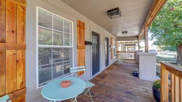 A covered porch with a table and chairs, wooden siding, and a view of the street.