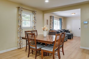 A dining area with a wooden table and chairs, a vase with flowers, and a view into the living room. - Home Near Historic Dtwn! 3 Mi to Occoneechee Mtn (Hillsborough)