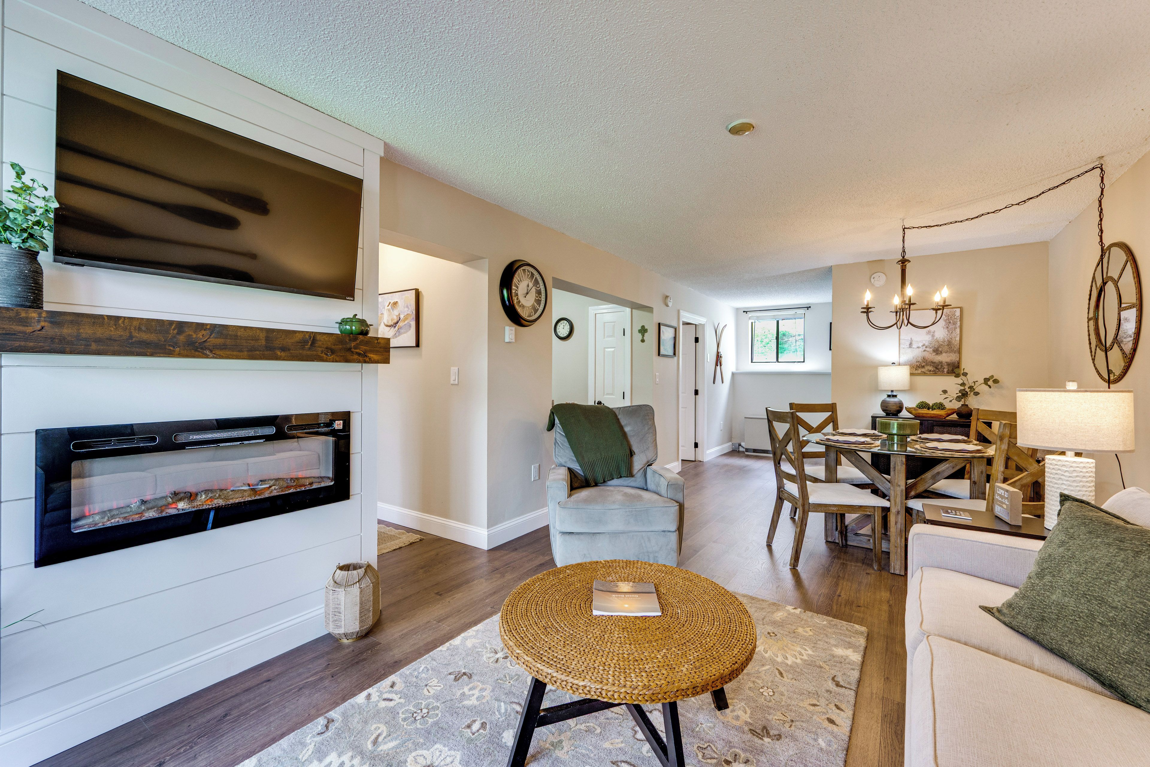 A living room with a fireplace, a dining area with a chandelier, and a hallway with a door.