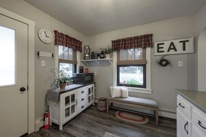 Cocina compacta con un reloj, un letrero que dice 'EAT' y un banco.