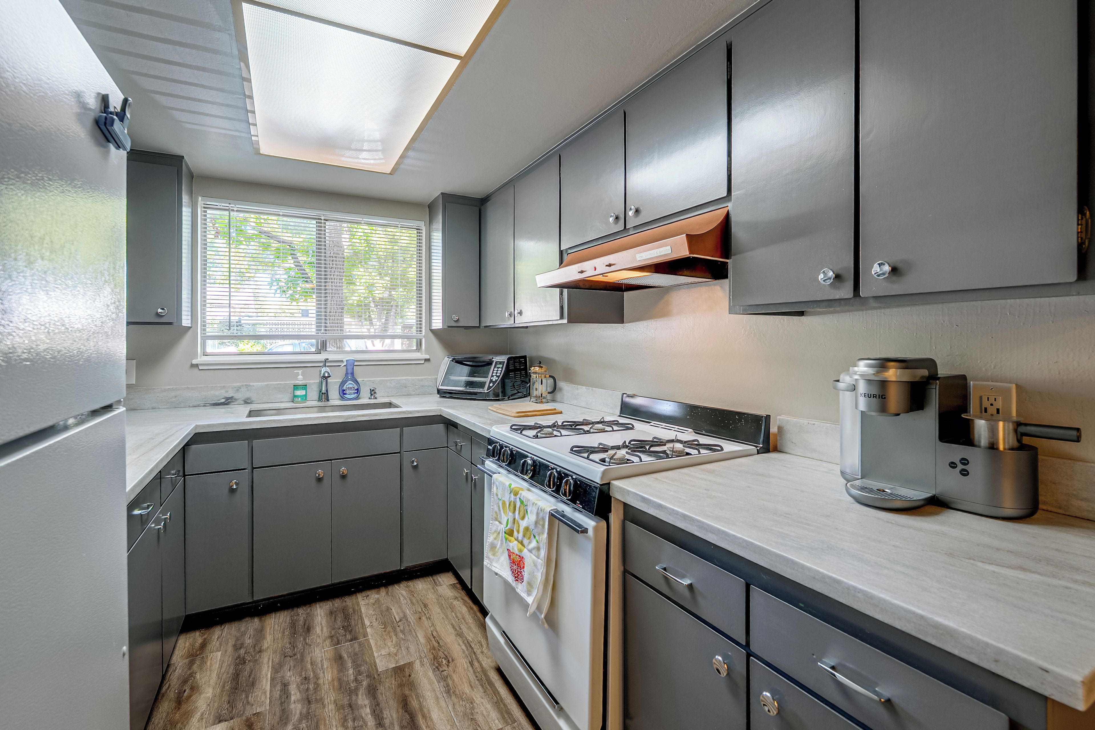 A modern kitchen with grey cabinets, a built-in stove, and a coffee maker.