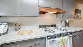 Una cocina con estufa a gas, cafetera y jarra de Hamilton Beach.