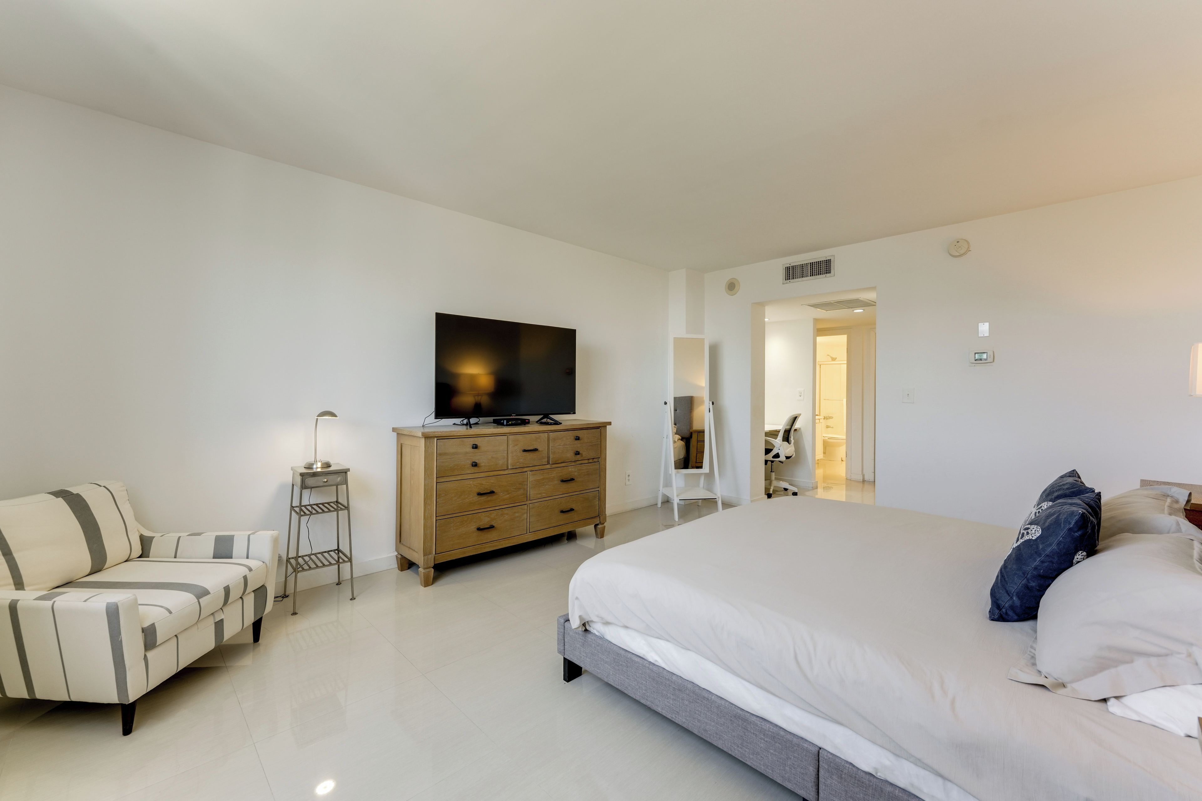 Un dormitorio con cama, televisor, cómoda y una silla.