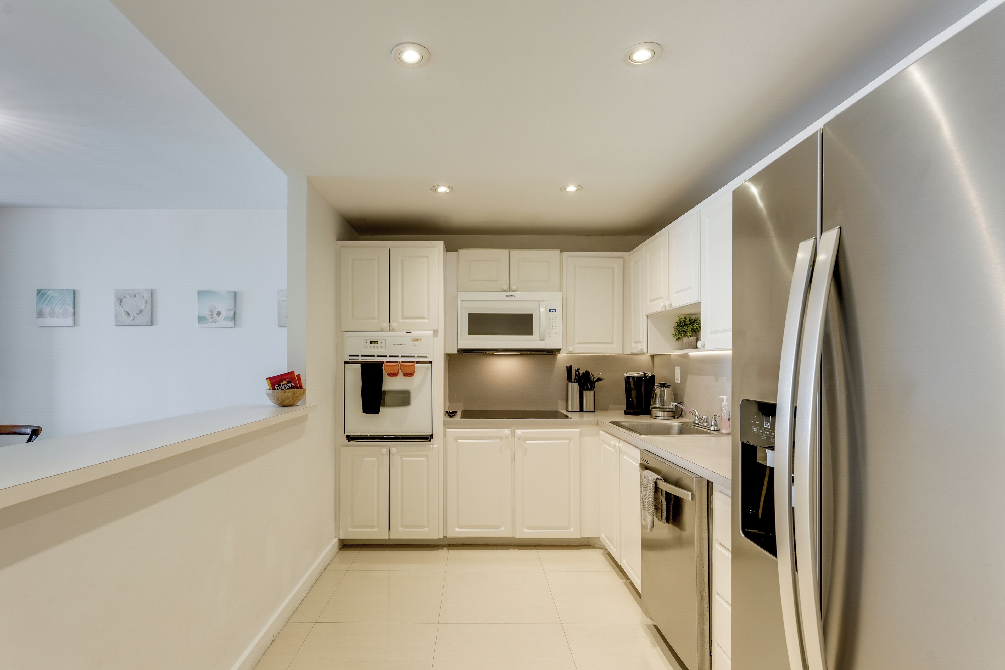 A modern kitchen with white cabinetry, a stainless steel refrigerator, and a built-in oven.