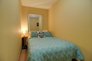 A bedroom with a bed, a nightstand, a lamp, and a wall-mounted mirror. - Grand Lake Escape: Deck, Hot Tub, Views! (Eucha)