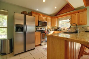 Una cocina con gabinetes de madera, electrodomésticos de acero inoxidable y encimera de granito.