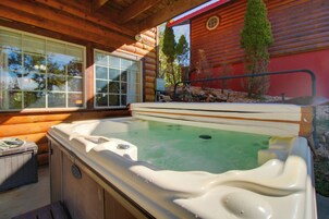 Un jacuzzi con cubierta de madera y ventana, con cabañas de madera al fondo.