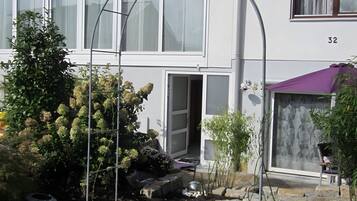 A residential building with a white facade, multiple windows, and a visible door.