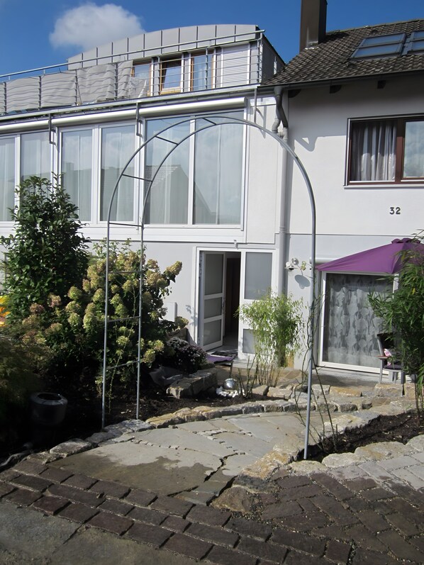 A residential building with a white facade, multiple windows, and a visible door.