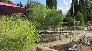 A garden with stone planters, a variety of plants, and a decorative metal sphere.