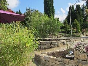 A garden with stone planters, a variety of plants, and a decorative metal sphere.