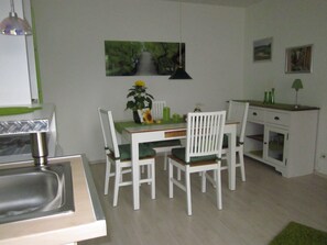 Eine kleine Küche mit Esstisch und Stühlen, einem Spülbecken und einem Schrank.
