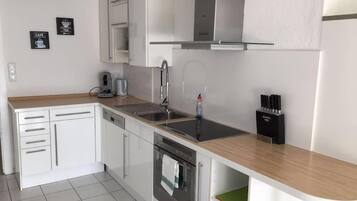 A modern kitchen with white cabinetry, stainless steel appliances, and a wooden countertop.