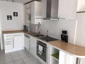 Eine moderne Küche mit weißen Schränken, Edelstahlgeräten und einer Holzausziehtafel.