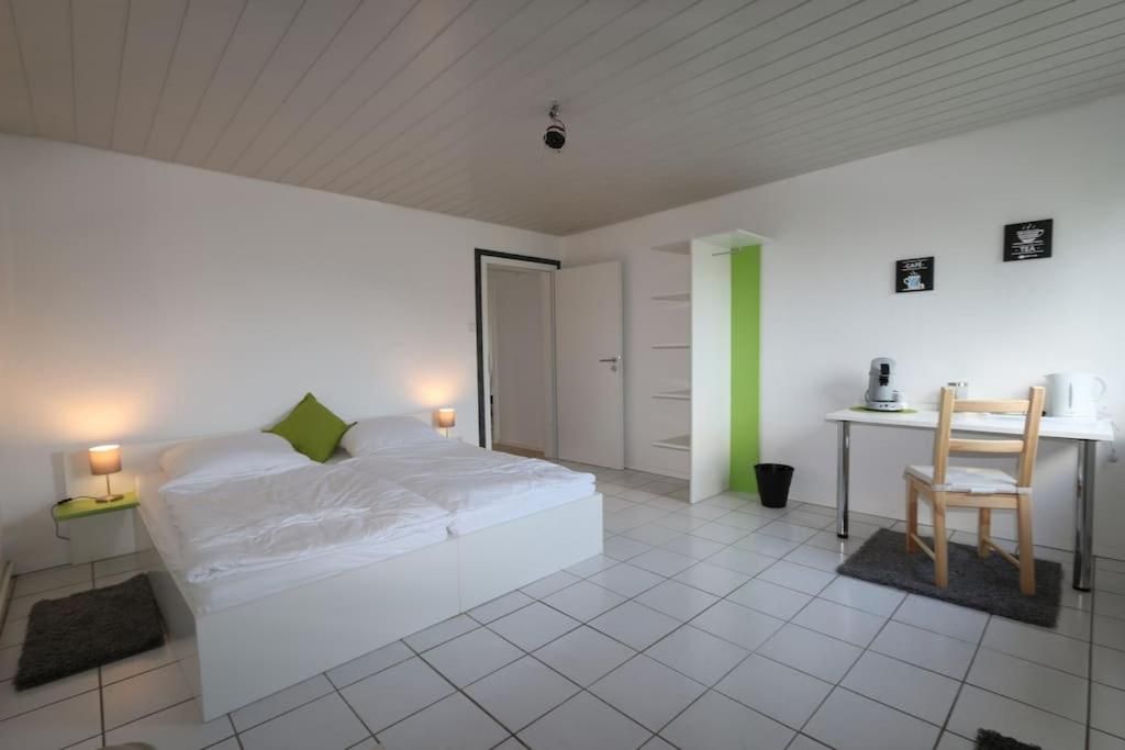 A bedroom with a bed, bedside table, and a desk with a chair.