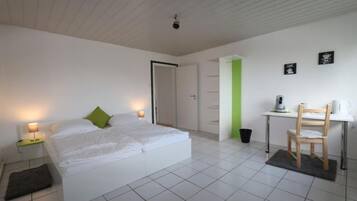 A bedroom with a bed, bedside table, and a desk with a chair.