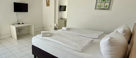 A bedroom with a bed, a bedside table, a TV, and a mirror.