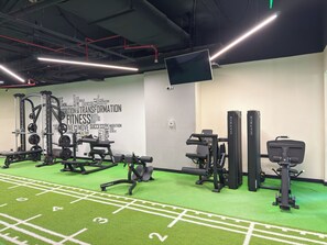 A gym with various exercise equipment, a green turf floor, and a wall with motivational words. - Palm Wellbeing Home with Beach, Pool & Gym (Dubai)