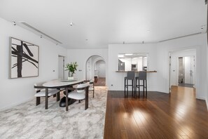 A modern kitchen with a central island, a dining area with a round table, and a hallway leading to other rooms. - Palm Wellbeing Home with Beach, Pool & Gym (Dubai)