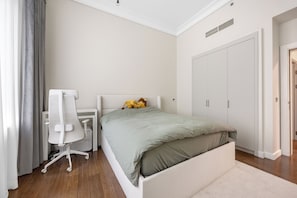A bedroom with a bed, a desk, a chair, and a wardrobe. - Palm Wellbeing Home with Beach, Pool & Gym (Dubai)