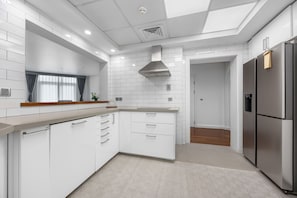 A modern kitchen with white cabinetry, a stainless steel refrigerator, and a patterned rug. - Palm Wellbeing Home with Beach, Pool & Gym (Dubai)