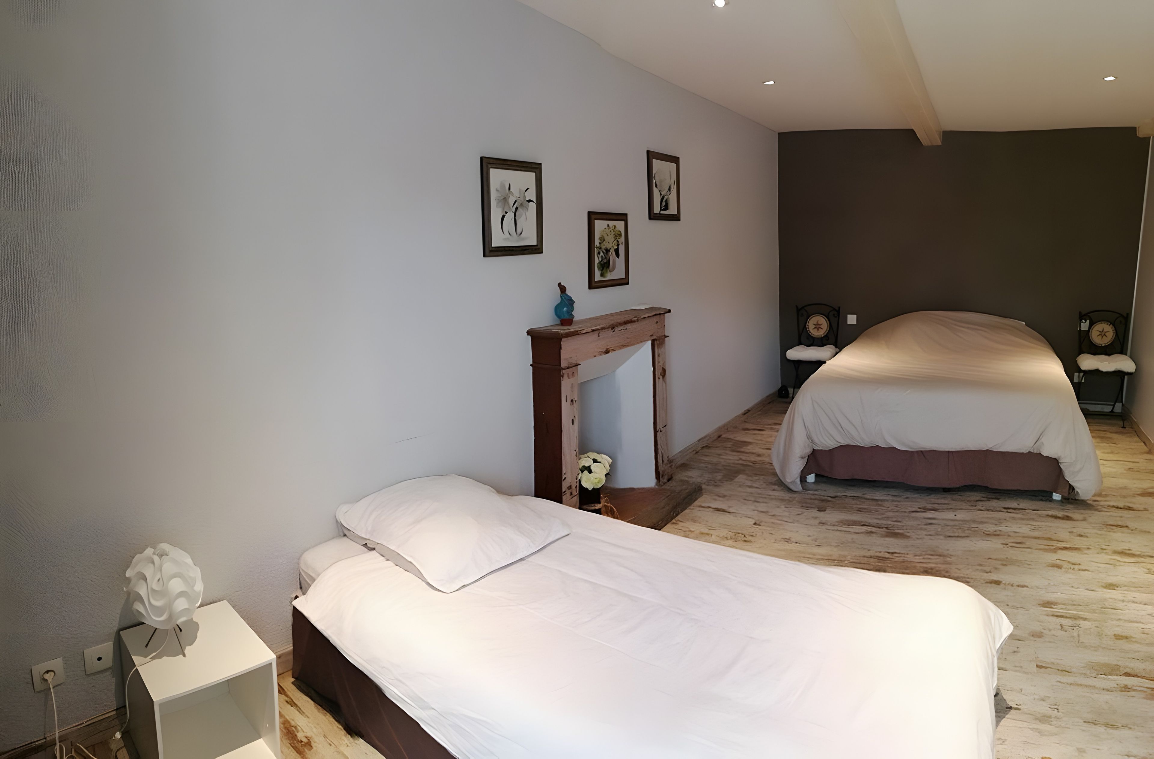 Une chambre avec deux lits, une table de chevet, une petite table avec un vase et des œuvres d’art murales.
