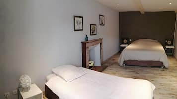 Een slaapkamer met twee bedden, een nachtkastje, een kleine tafel met een vaas en wanddecoratie.