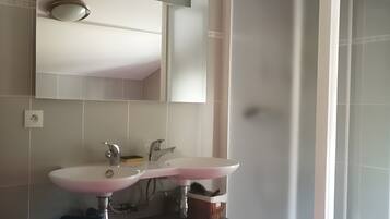 A bathroom with a white sink, mirror, and shower enclosure.