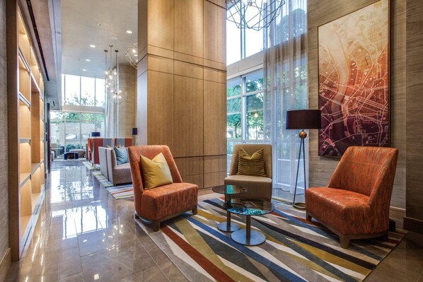 Eine moderne Lobby mit Ledersesseln, einem Glastisch und einem großen abstrakten Wandbild.