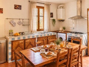 A kitchen with a dining table set for breakfast, a washing machine, and a stove. - Private Tuscan Cottage in Chianti - Breakfast at Home Near Florence (Greve in Chianti)