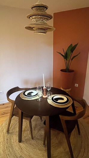 Una mesa de comedor con una araña, dos sillas, una planta en maceta y una vela.