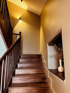 A wooden staircase with a handrail, a wall-mounted light, and a shelf with a vase. - A 150-square-meter home with a private spa and a view of the Lot—just for the two of you! (bellefont laroque)