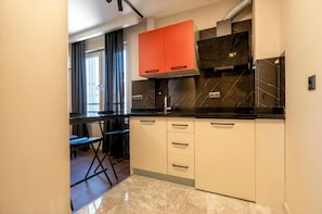 A modern kitchen with a black countertop, white cabinets, and a red upper cabinet. - Premium Rezidans Otel (Muratpasa)