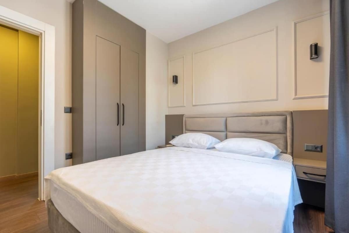 A hotel room with a large bed, a wardrobe, and a bedside table.