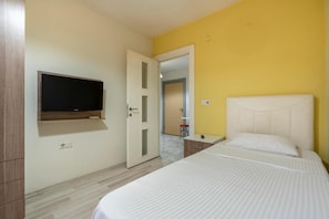 A bedroom with a bed, a TV mounted on the wall, and a door leading to another room. - Premium Rezidans Otel (Muratpasa)