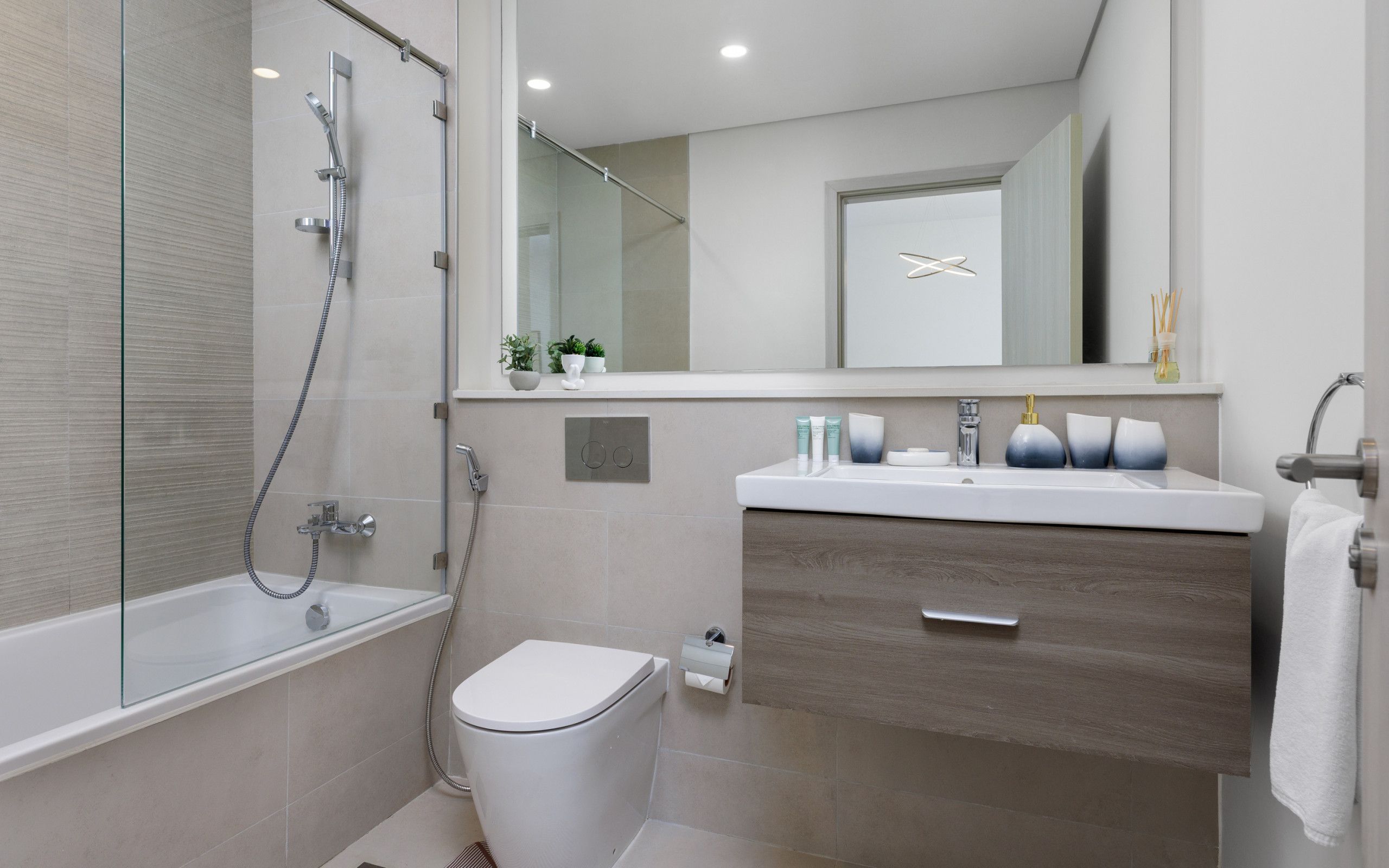 A modern bathroom with a glass-enclosed shower, a white toilet, a vanity with a mirror, and a towel rack.