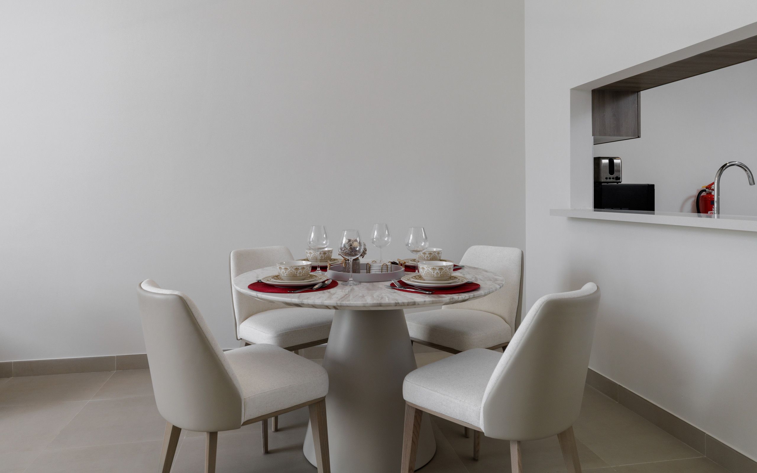A modern dining area with a round table set for four, white chairs, and a minimalist design.