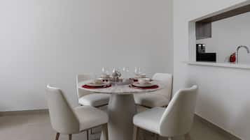 A modern dining area with a round table set for four, white chairs, and a minimalist design.