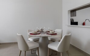 Ein moderner Essbereich mit einem runden Tisch für vier Personen, weißen Stühlen und einem minimalistischen Design.