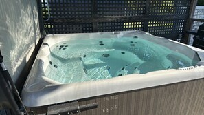 A hot tub with a wooden deck surrounding it. - Camper off the beaten path. (Lakeshore)
