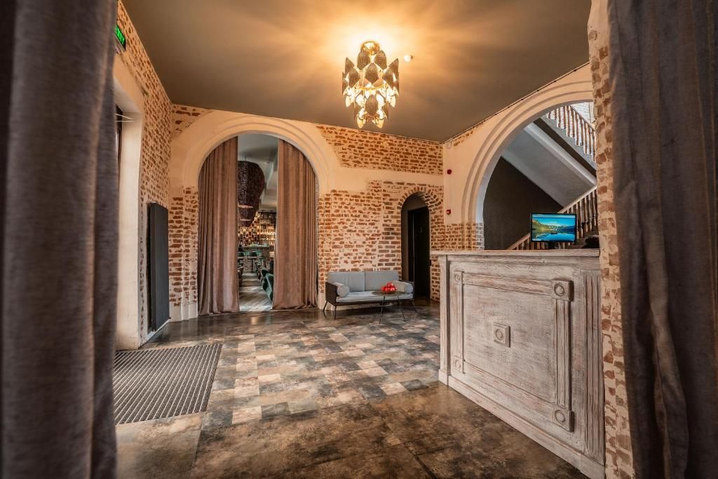 Un hall d’entrée spacieux avec un sol à carreaux, un lustre et un téléviseur posé sur un meuble.