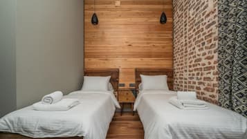 A room with two beds, wooden headboards, and a brick-patterned wall.