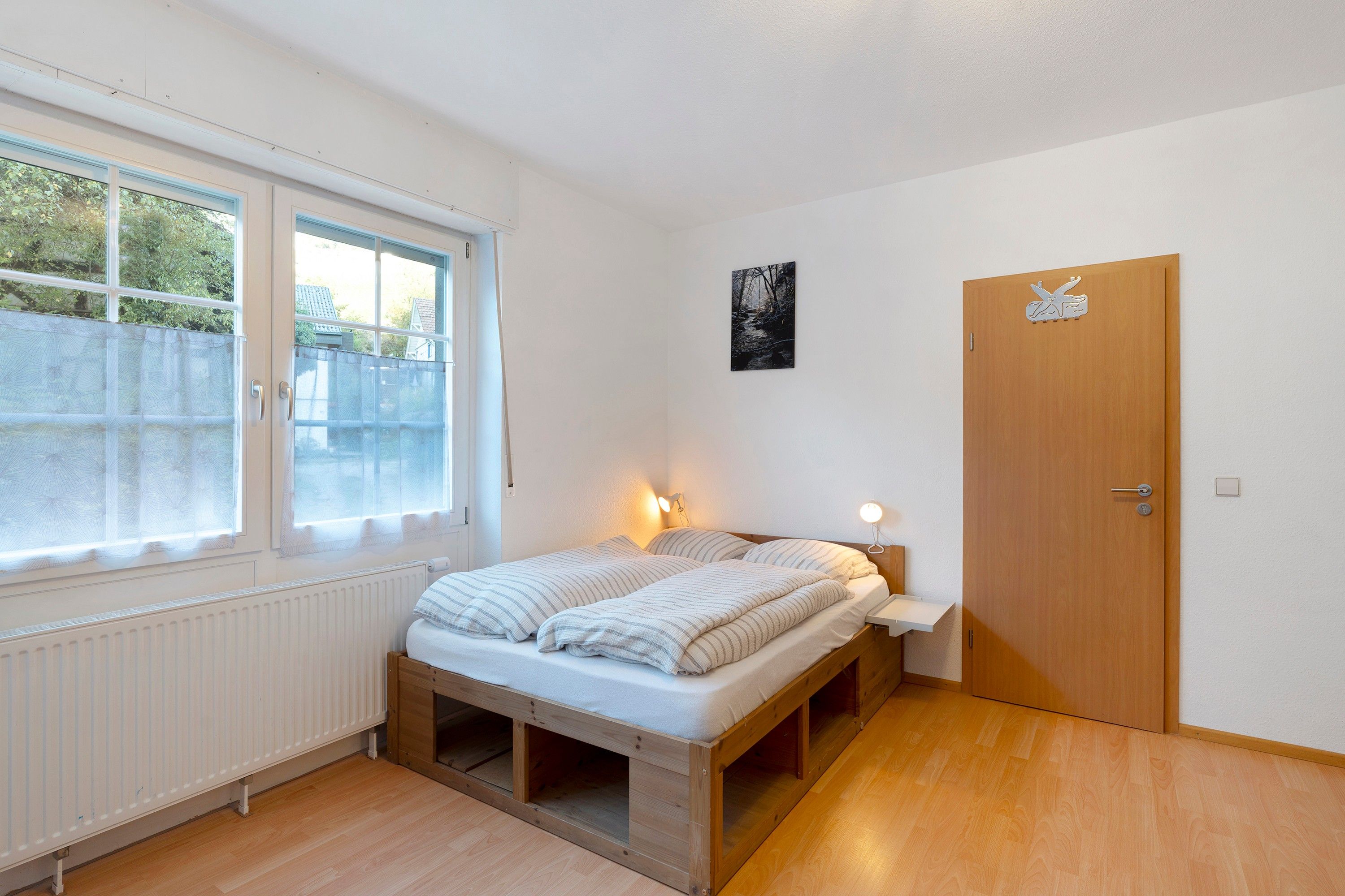Un dormitorio pequeño y ordenado con una cama individual, una ventana y una puerta.