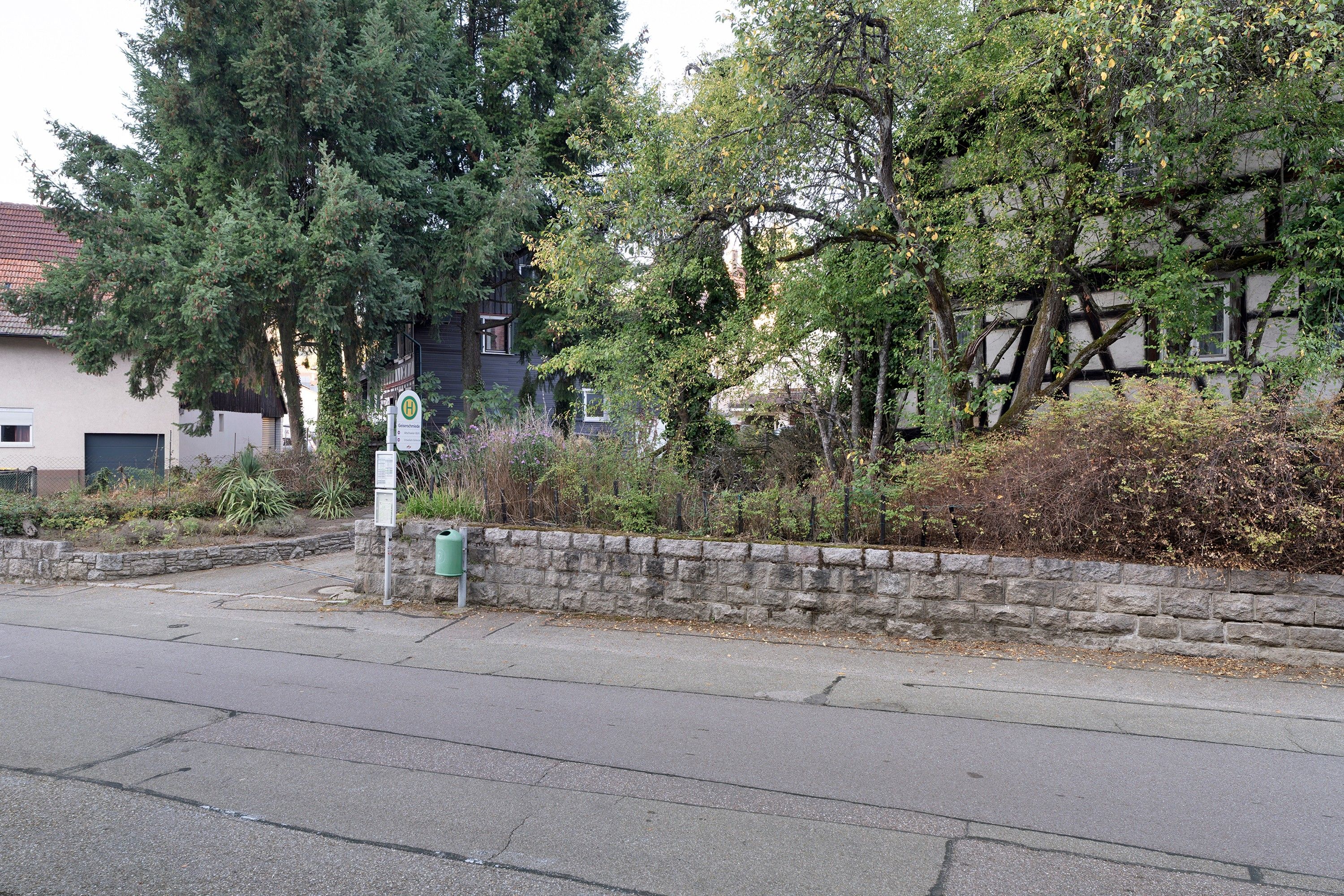 A street with a stone wall, a street sign, and a building with a dark facade.